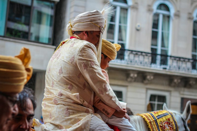 A groom in a turban riding in a baraat procession